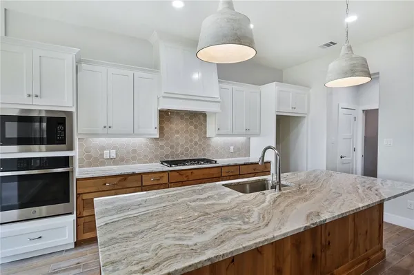 a kitchen with kitchen island granite countertop a stove a sink and a white cabinets