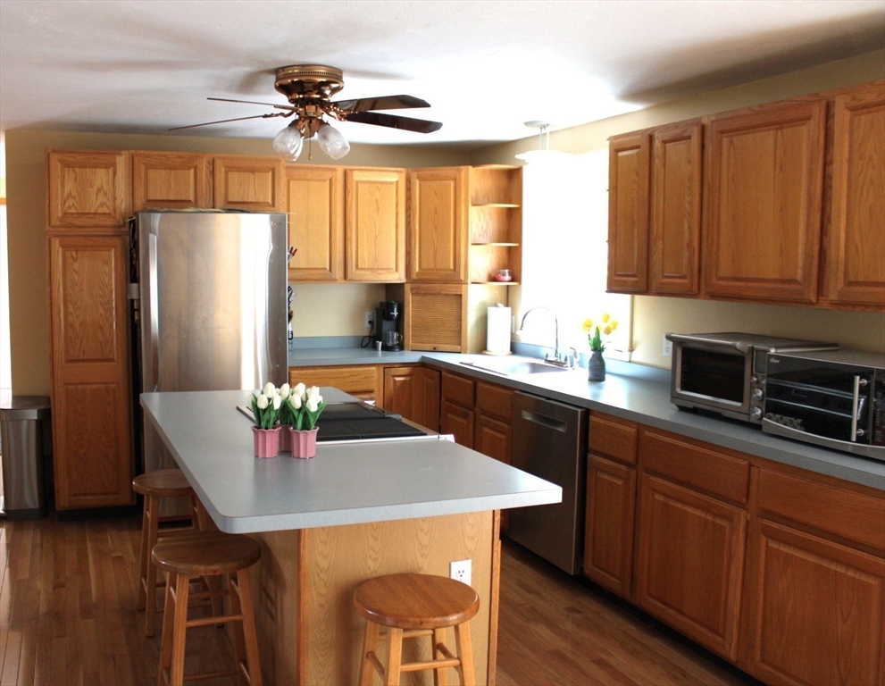 27 Gretchen Way Raynham, MA 02767 - Photo 5 of 20 a kitchen with stainless steel appliances granite countertop a sink a microwave cabinets and wooden floor