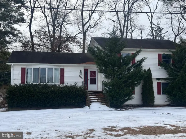 a front view of house with yard and trees in the background