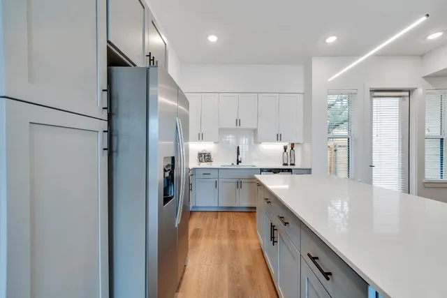 a large kitchen with stainless steel appliances kitchen island granite countertop a refrigerator and a sink