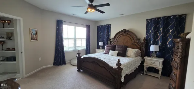 a bedroom with a bed lamp closet and three large window