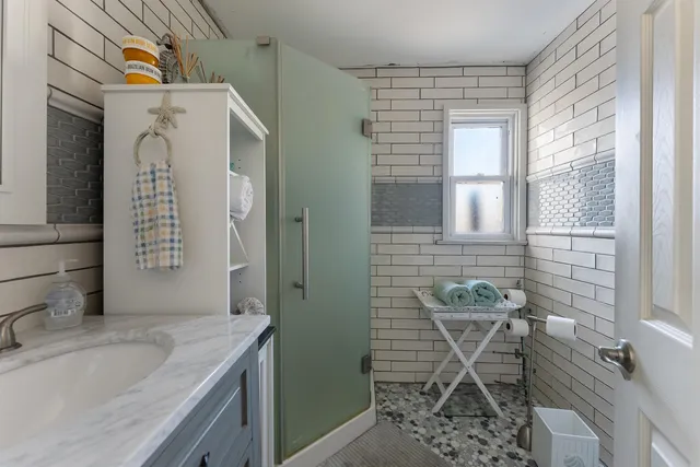 a bathroom with a granite countertop sink a mirror and a shower