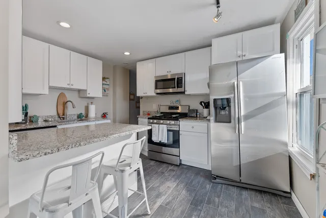 a kitchen with granite countertop a refrigerator stove and microwave