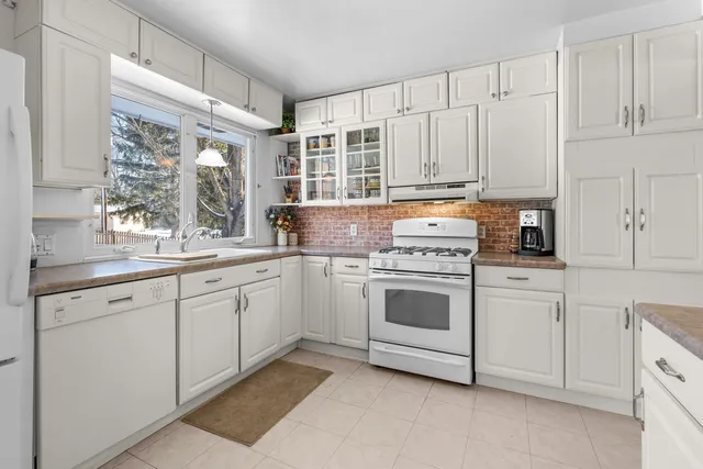 a kitchen with cabinets appliances a sink and a window