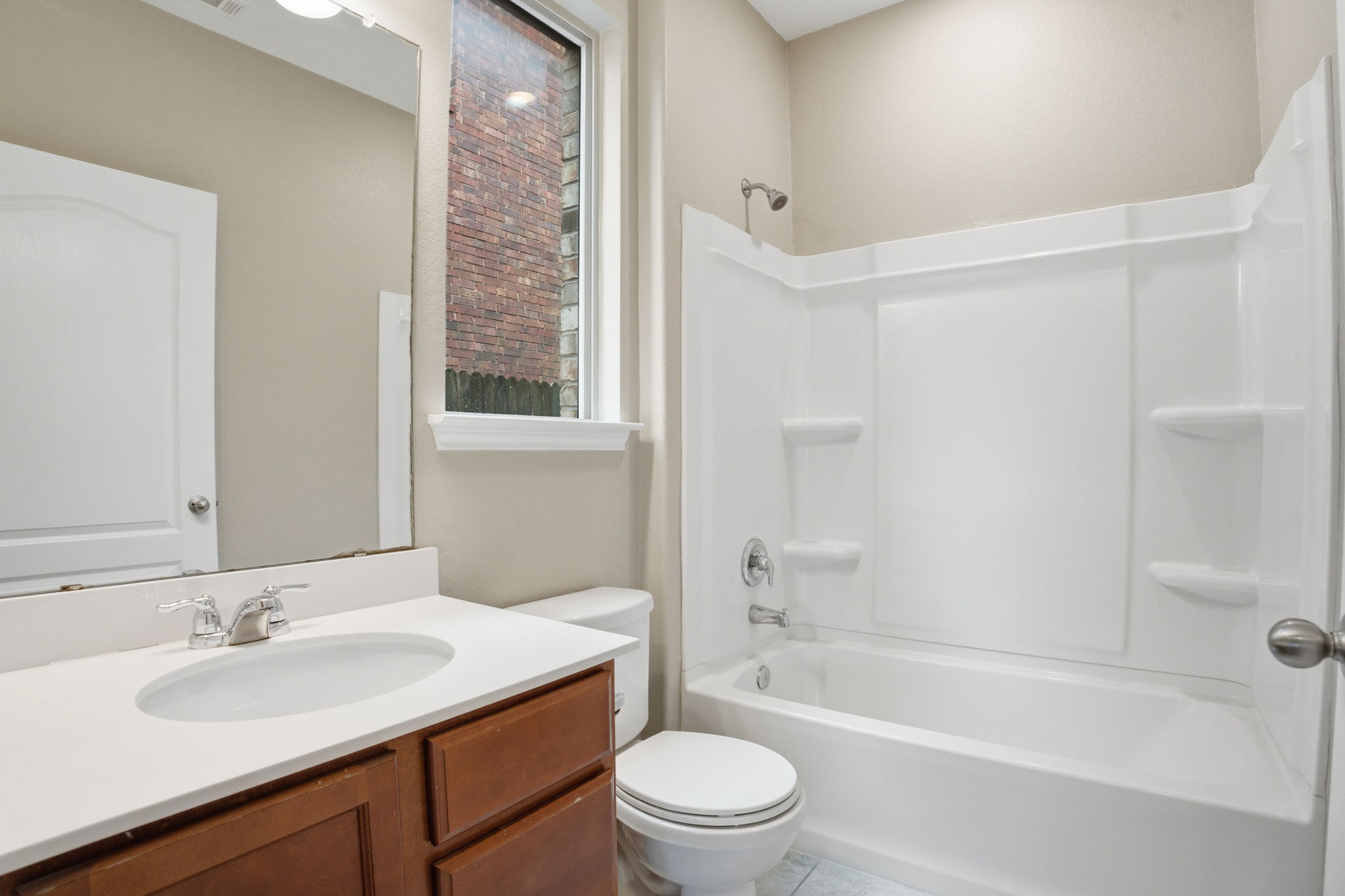 670 Landon Samuel Loop Pflugerville, TX 78660 - Photo 18 of 22 Bathroom featuring a white integrated sink and countertop, wood-finish vanity with cabinet storage, and a white tub/shower combination with integrated shelving