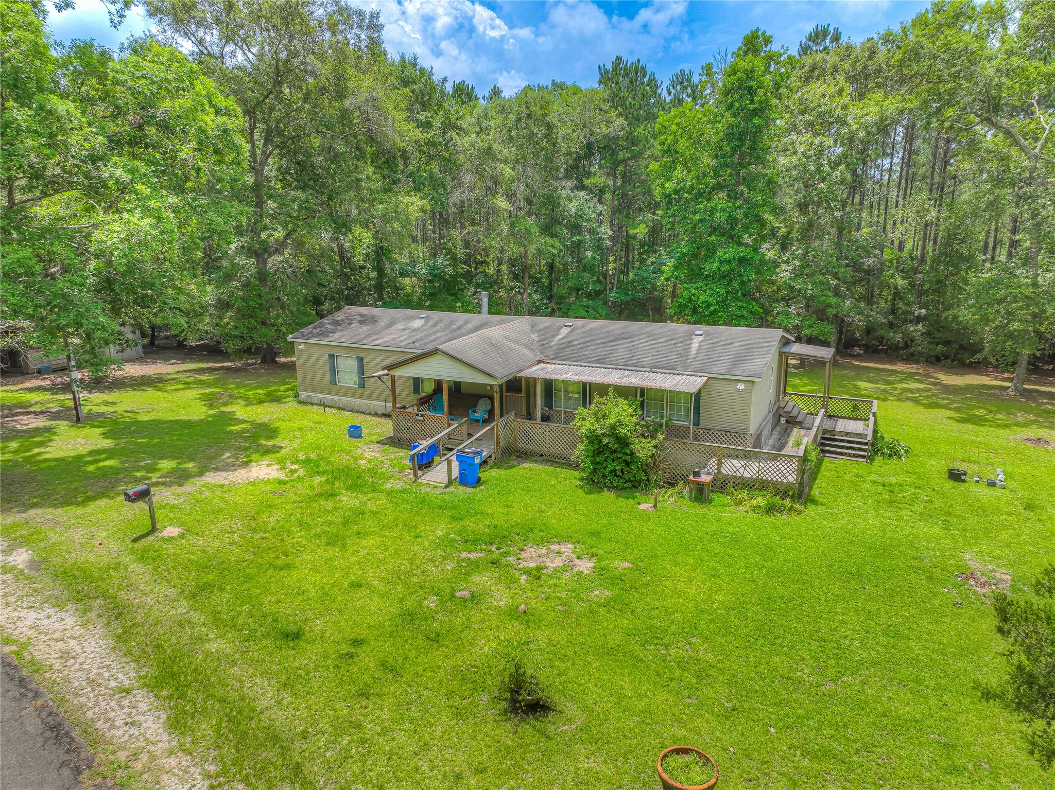 657 Parrish Road Livingston, TX 77351 - Photo 2 of 47 a view of a house with a big yard potted plants and large tree