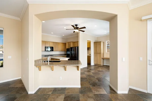 a view of a kitchen with kitchen island a counter top space appliances and a ceiling fan