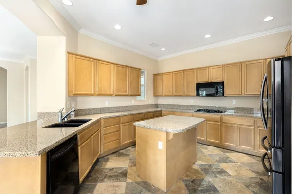 a kitchen with stainless steel appliances granite countertop a sink a stove a refrigerator a microwave a sink and cabinets