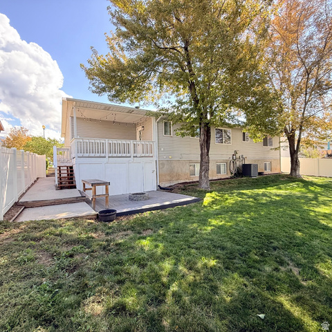 10240 Locksley Road Sandy, UT 84092 - Photo 23 of 27 Expansive backyard featuring a covered deck, lower patio with fire pit, and white privacy fencing