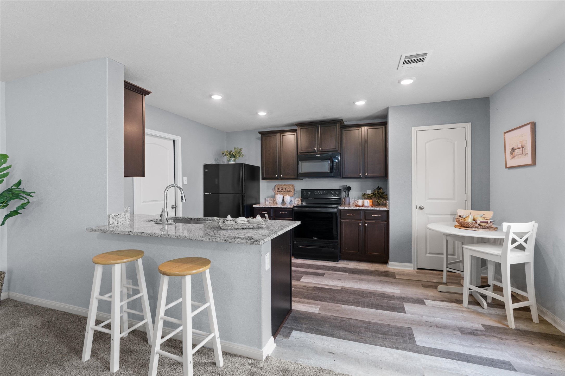 163 Niven Path, Unit 12K Jarrell, TX 76537 - Photo 10 of 31 a kitchen with kitchen island granite countertop stainless steel appliances a stove a refrigerator a sink a dining table and chairs