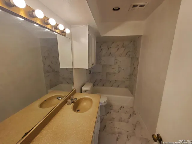 a bathroom with a granite countertop sink a toilet and shower