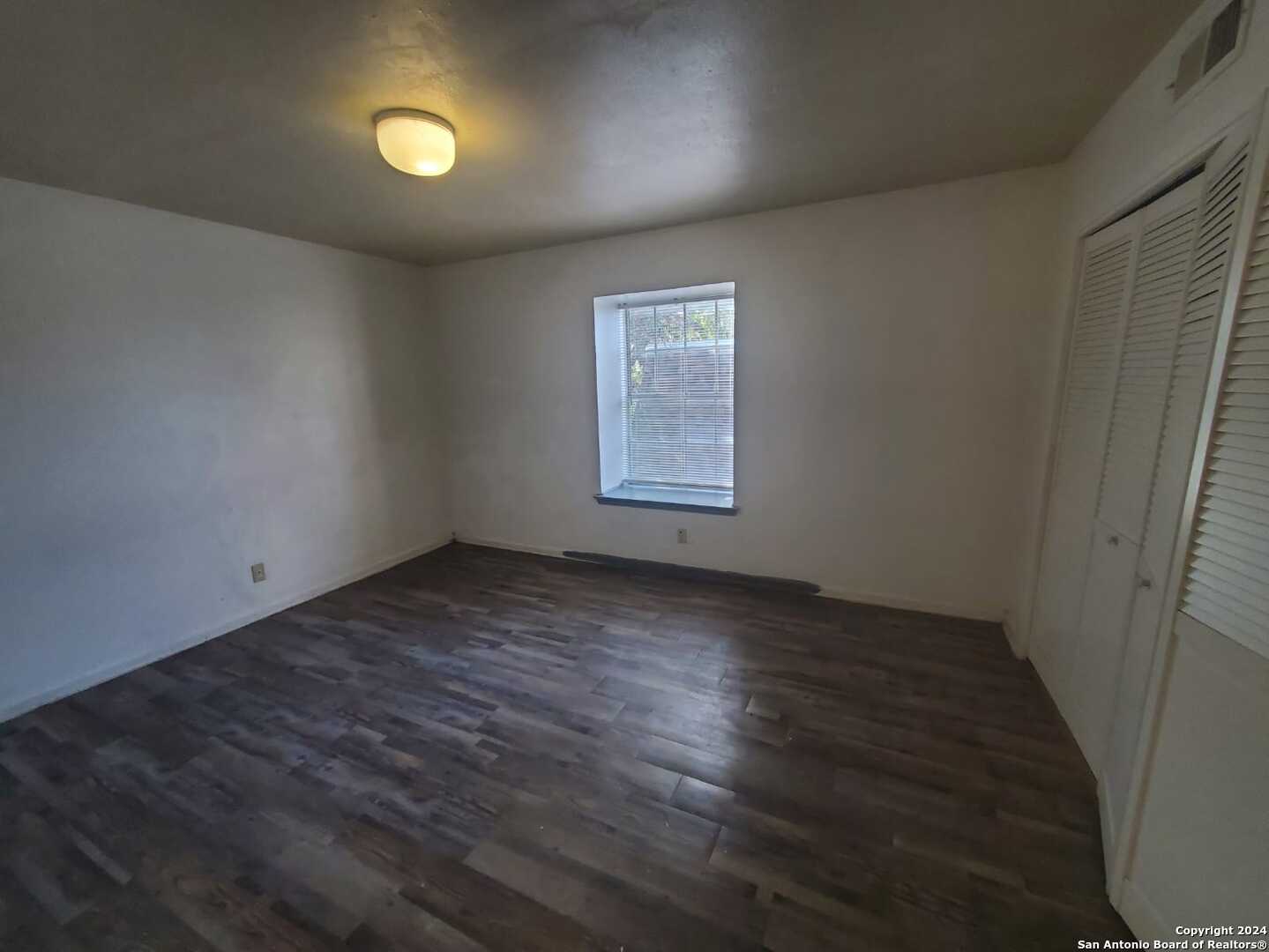 170 De Chantle Road, Unit 208 San Antonio, TX 78201 - Photo 13 of 14 an empty room with wooden floor and windows
