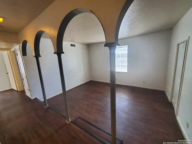 an empty room with wooden floor and entrance