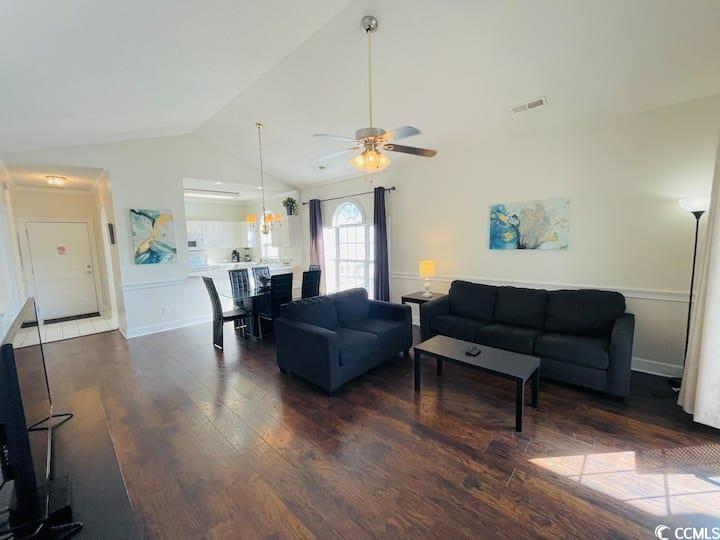 4631 Wild Iris Drive, Unit 301 Myrtle Beach, SC 29577 - Photo 7 of 37 Living room featuring lofted ceiling, dark wood-type flooring, and a ceiling fan