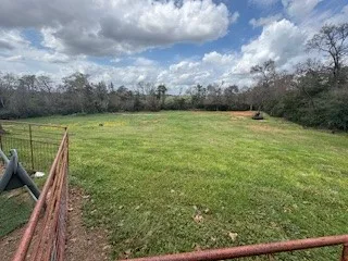 a view of a green field with wooden fence