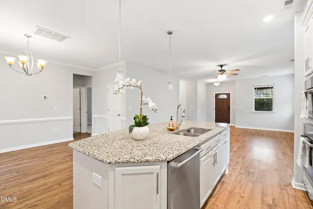 a hall with kitchen island granite countertop a sink and a wooden floor