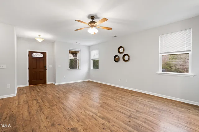 a view of an empty room with window and wooden floor