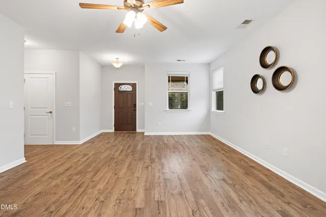 a view of an empty room with wooden floor and windows
