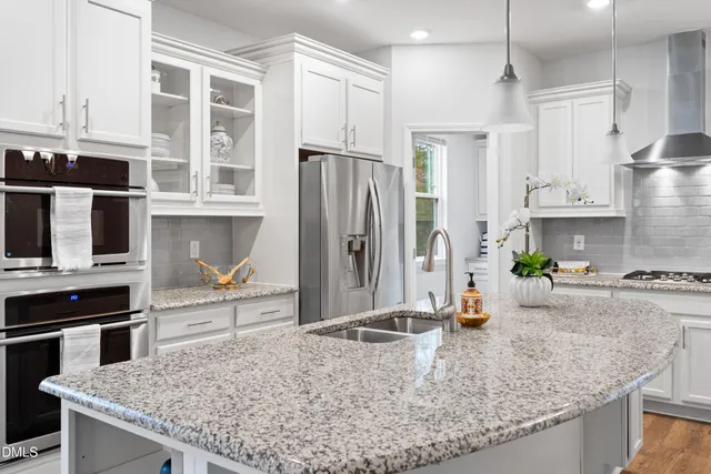 a kitchen with stainless steel appliances granite countertop a sink a stove and a refrigerator