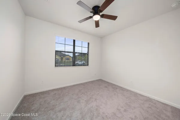 an empty room with a window and ceiling fan