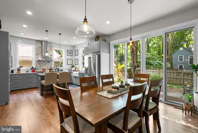 a dining room with stainless steel appliances granite countertop a table chairs and a view of living room