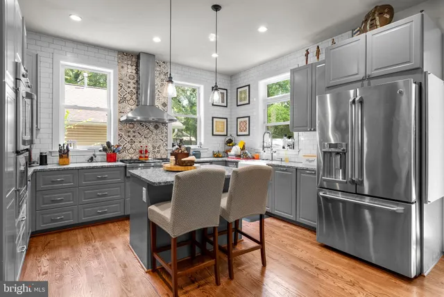 a kitchen with kitchen island a large counter top space appliances and windows