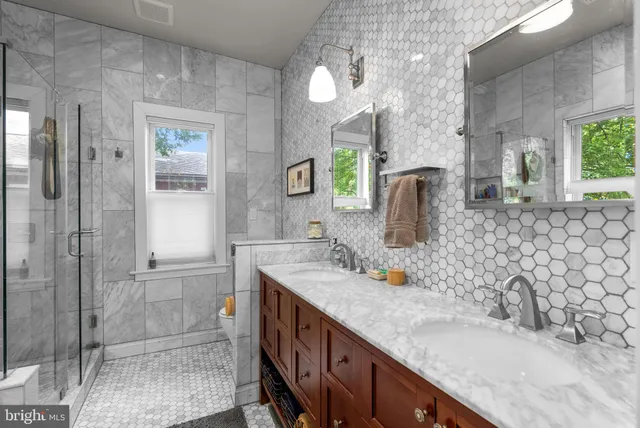 a bathroom with a granite countertop sink a mirror and shower