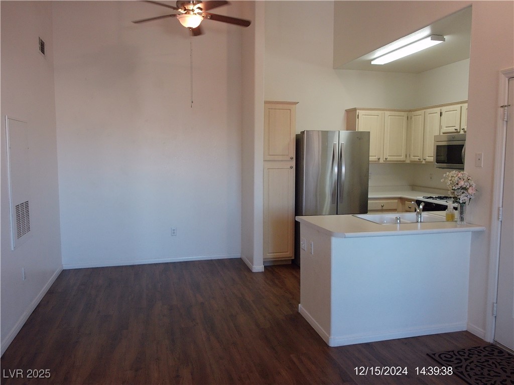 855 North Stephanie Street, Unit 2526 Henderson, NV 89014 - Photo 7 of 26 Kitchen featuring light countertops, stainless steel microwave, a ceiling fan, dark wood finished floors, and a peninsula
