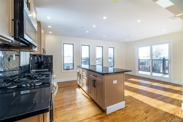 a large kitchen with stainless steel appliances granite countertop a stove and a large window