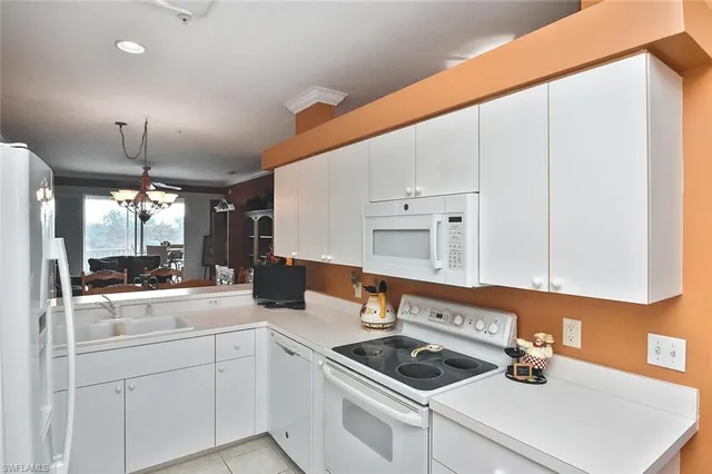 a kitchen with stainless steel appliances kitchen island granite countertop a refrigerator a sink and white cabinets