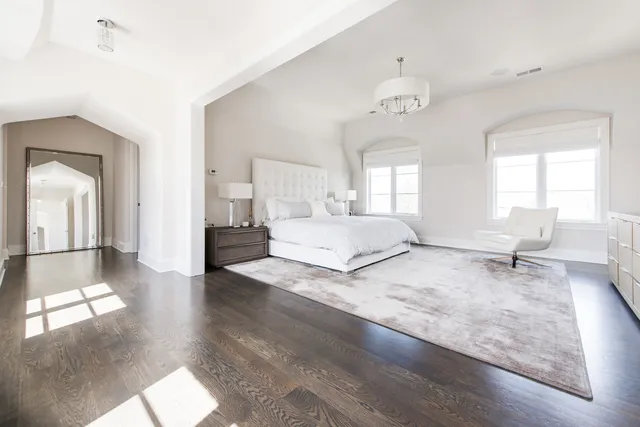 a spacious bedroom with a bed a chandelier and a window