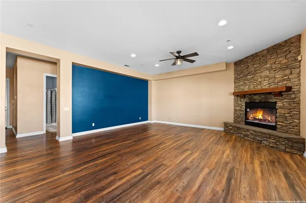 a view of an empty room with wooden floor fireplace and a window