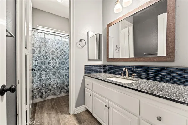 a bathroom with a granite countertop sink a mirror and a shower