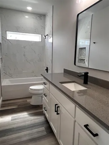a bathroom with a granite countertop sink a toilet a mirror and shower