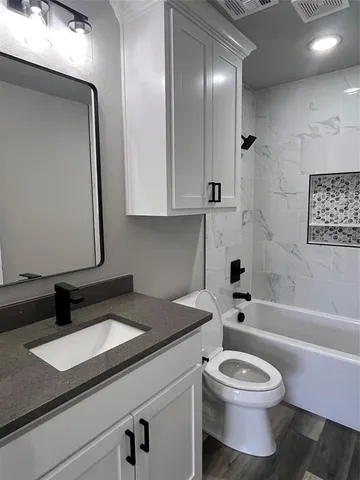 a bathroom with a granite countertop sink toilet a mirror and bathtub