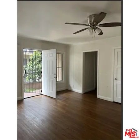 a view of an empty room with wooden floor and a window