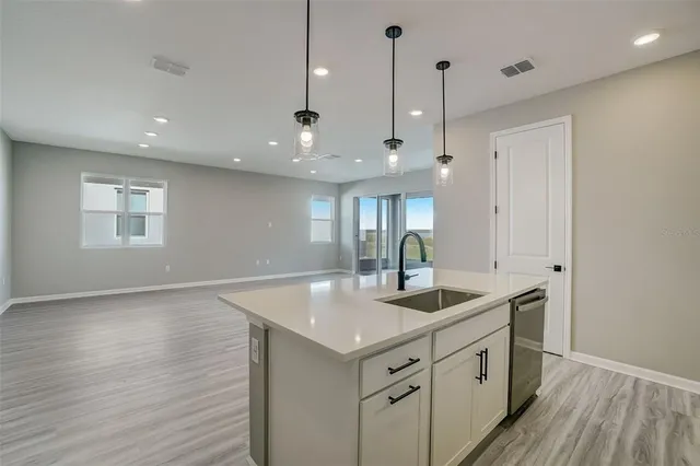 a kitchen with a sink chandelier and wooden floor