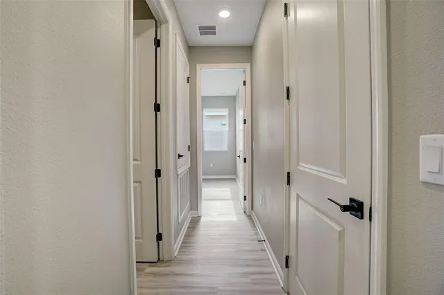 a view of a hallway with wooden floor and a bathroom