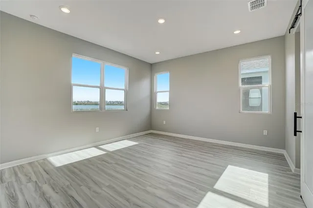 a view of an empty room with wooden floor and closet