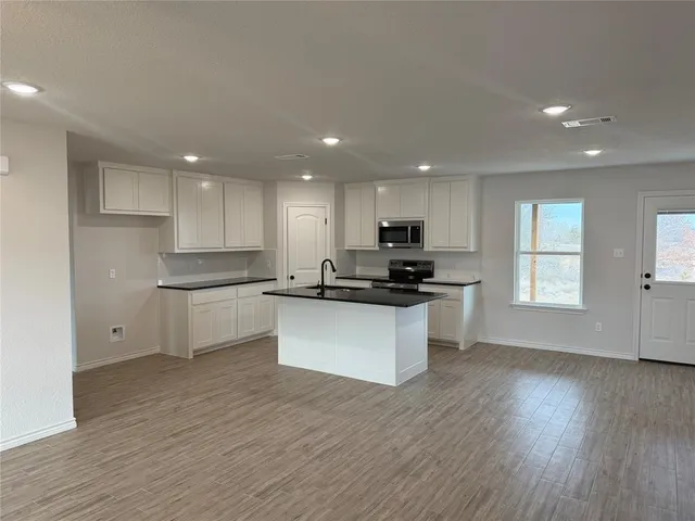 a kitchen with a refrigerator and white cabinets