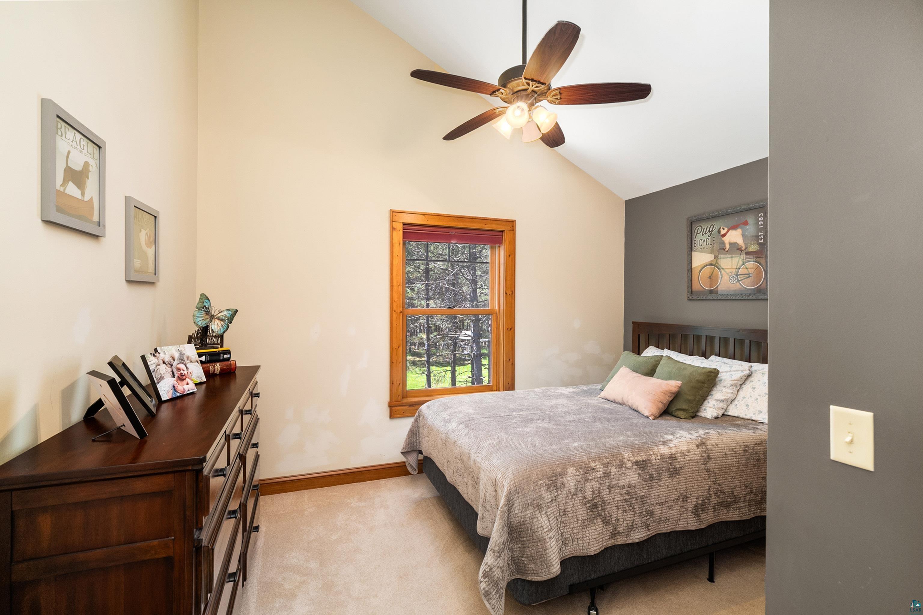75 East Stark Road Esko, MN 55733 - Photo 31 of 87 Vaulted ceiling with a ceiling fan, window with natural wood trim, plush carpet flooring, dark wood-tone dresser, and a dark wood-tone bed frame