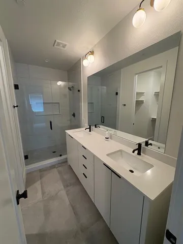a bathroom with a double vanity sink mirror and shower