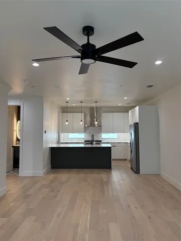 a view of a big room with wooden floor and chandelier fan