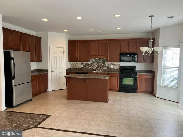 a kitchen with stainless steel appliances granite countertop a stove top oven a refrigerator and a sink with wooden floor