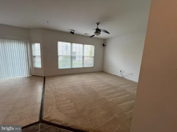 an empty room with windows and ceiling fan