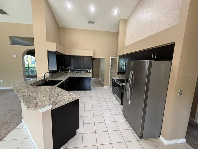 a kitchen with a sink a microwave a refrigerator and chairs