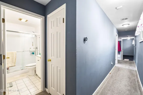 a view of a hallway with wooden floor and a bathroom