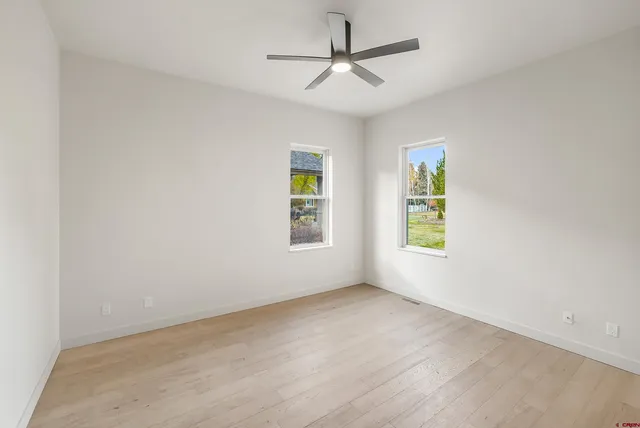an empty room with windows and fan