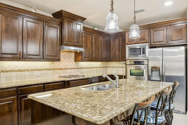 a kitchen with kitchen island granite countertop wooden cabinets stools and a stainless steel appliances