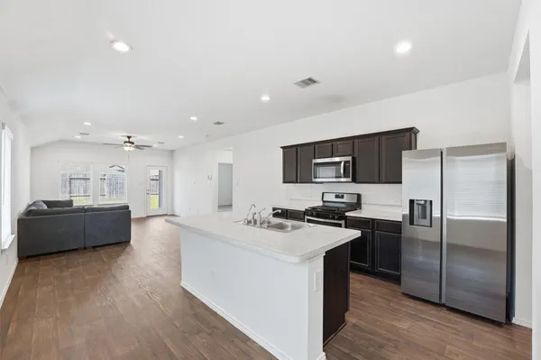 a large white kitchen with a refrigerator a stove a microwave oven with white cabinets and wooden floor